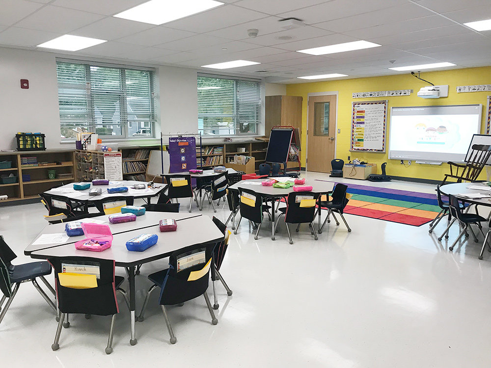 a classroom with tables, chairs, and a projector screen