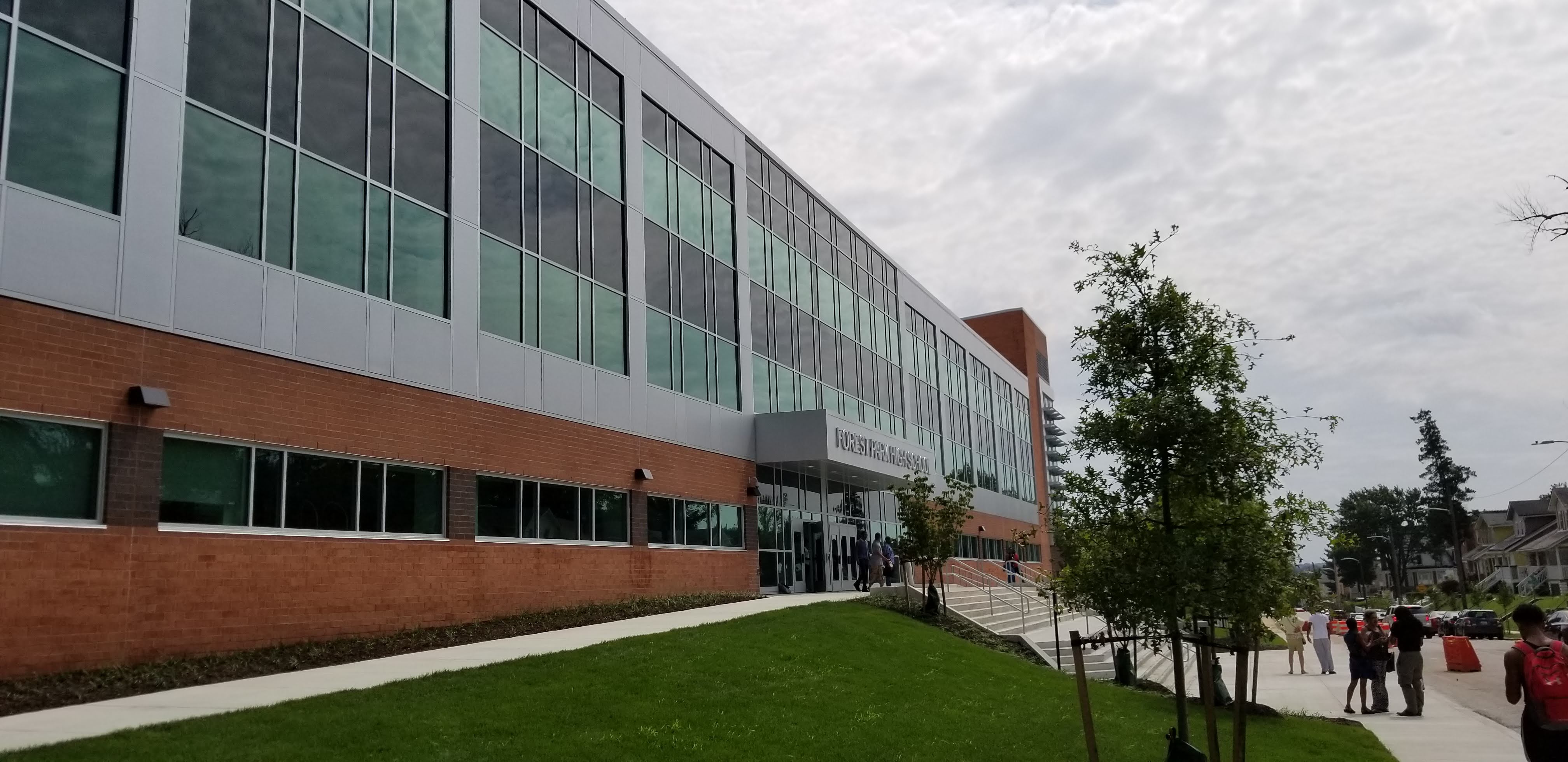 a group of people walking down a sidewalk next to a building