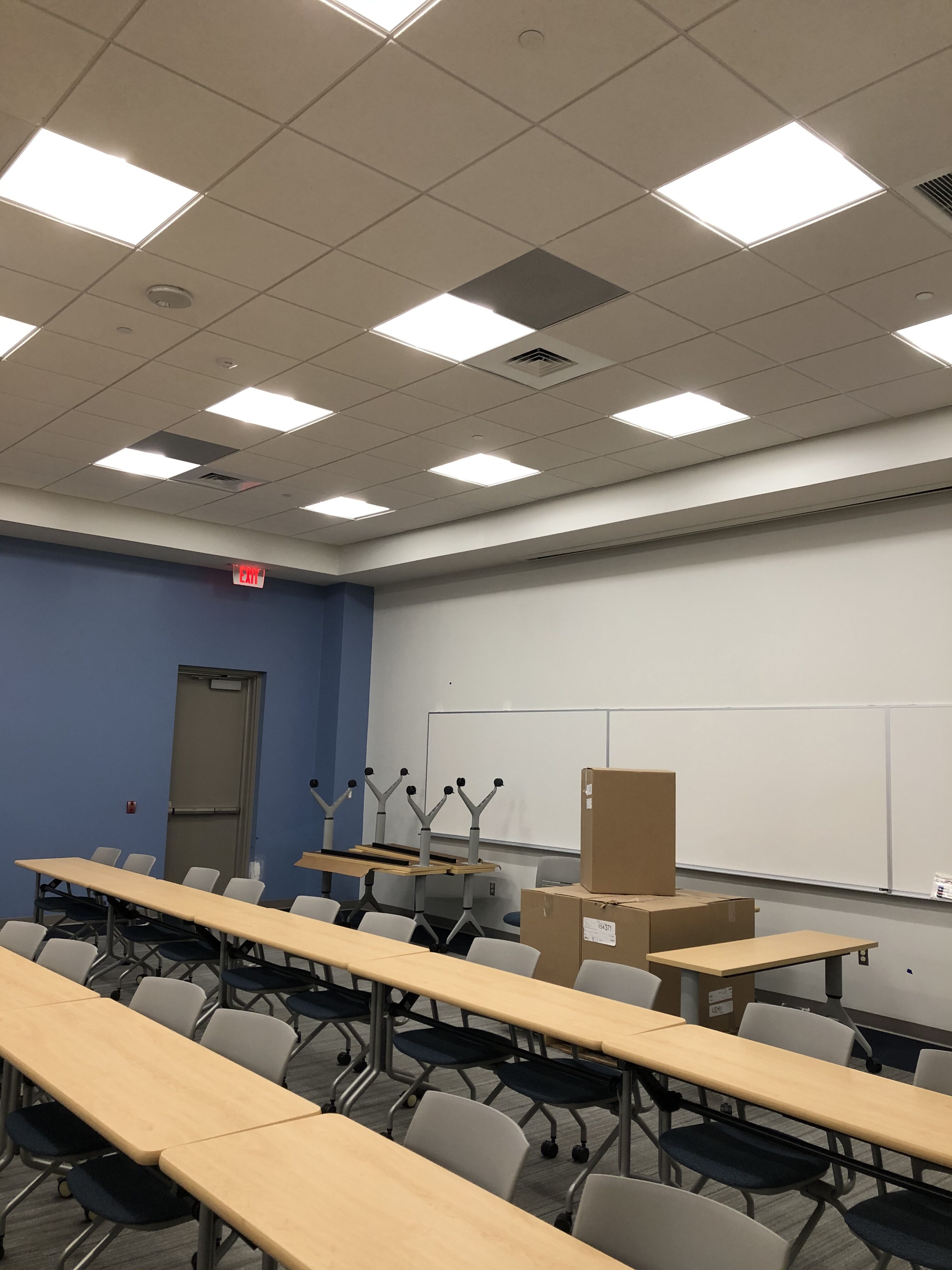 an empty classroom with desks and a projector screen