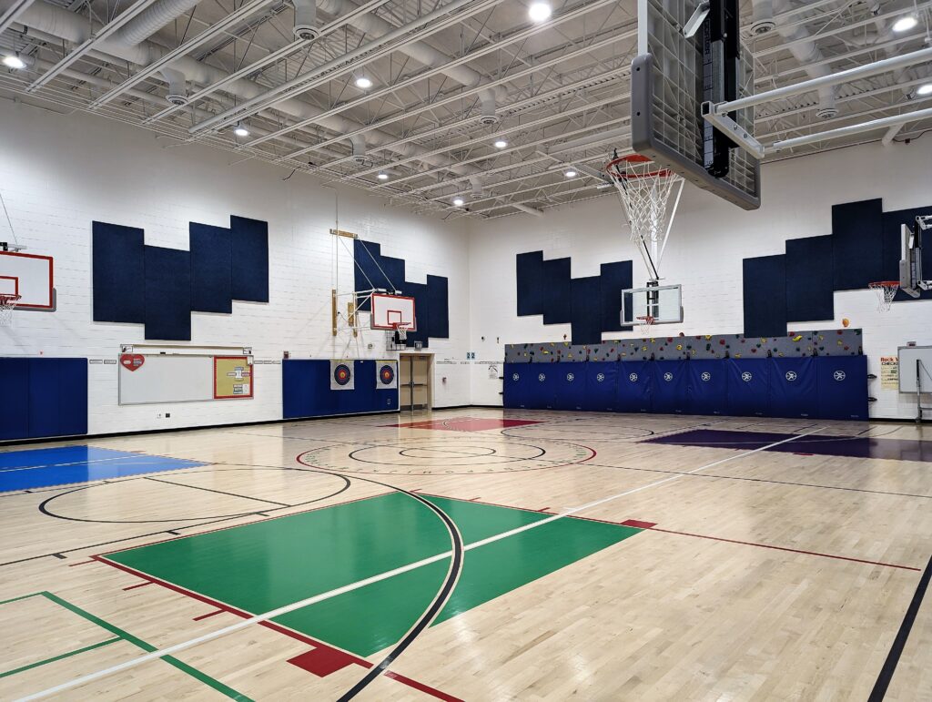 an empty gym with a basketball court and basketball hoop