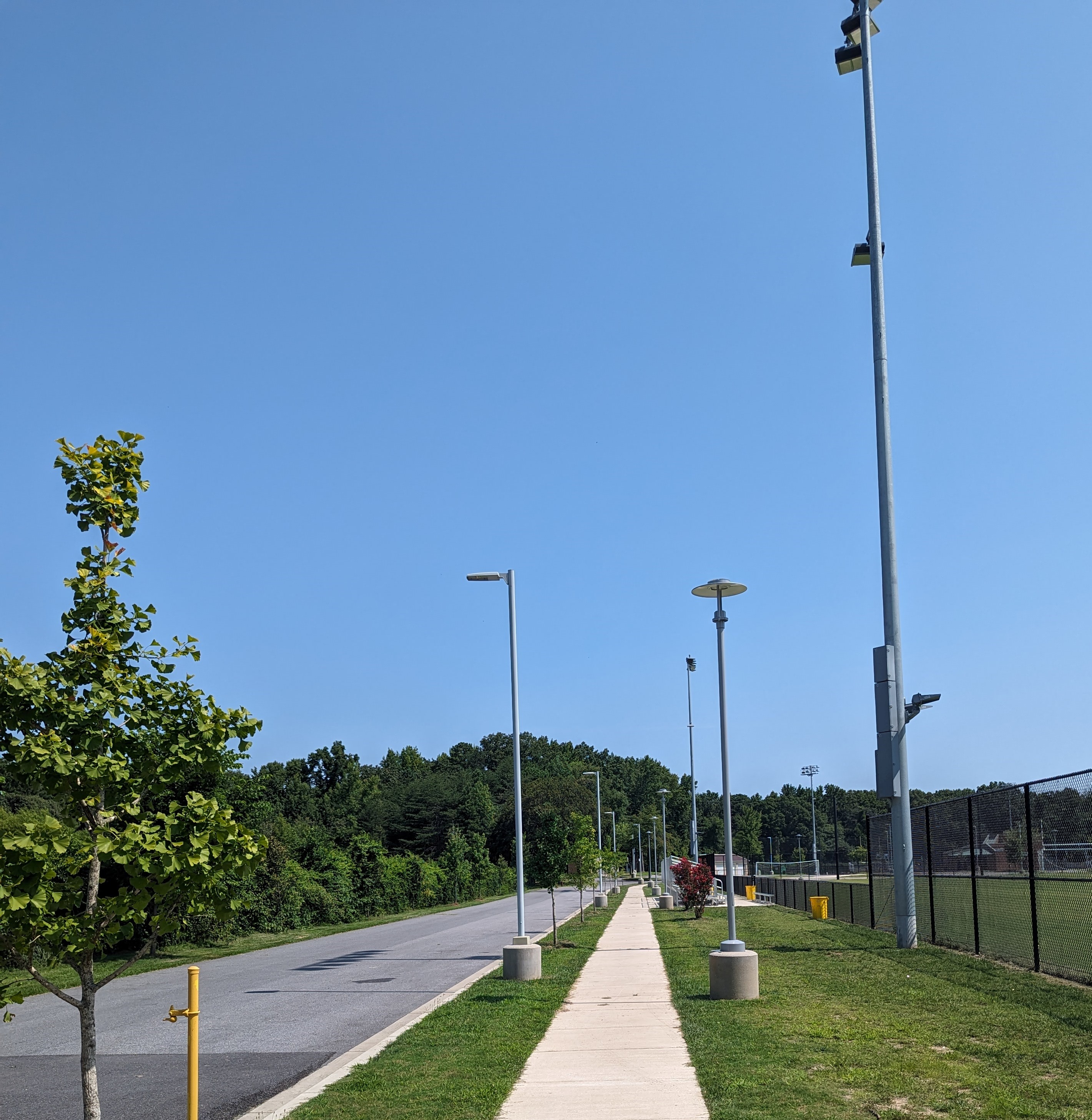 a long sidewalk next to a grassy field